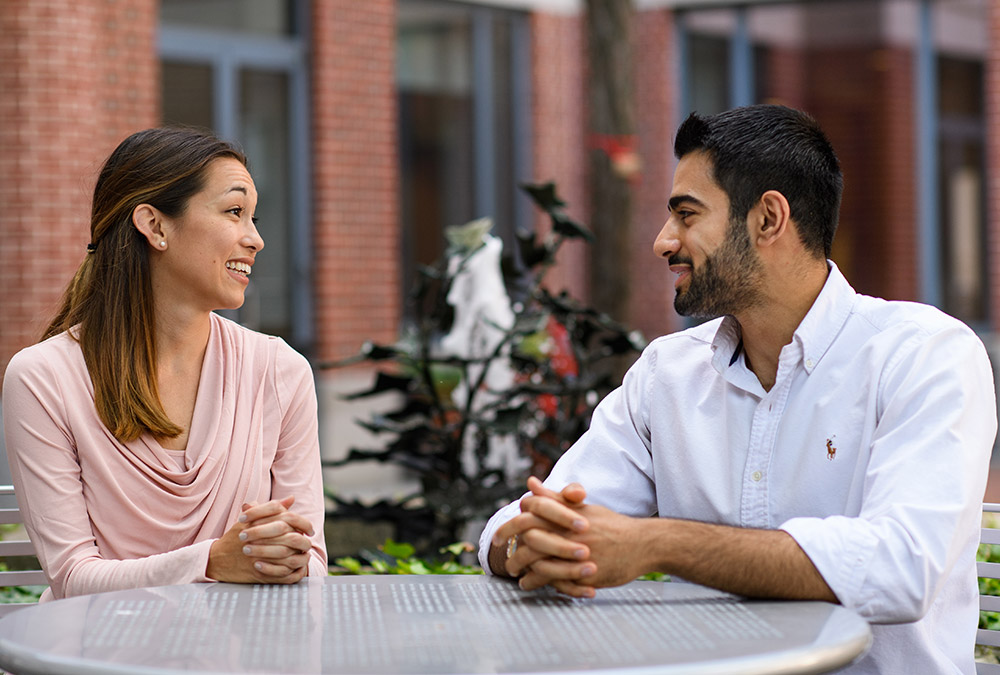 Jennifer Caughey DMD/ML ’19, Mohammad Mousavian DMD ‘19/ML’18 Jennifer Caughey and Mohammad Mousavian talking at a table